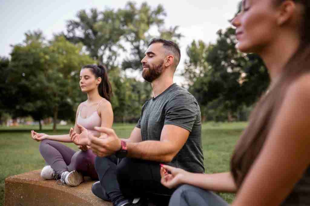 Three people meditating outdoors