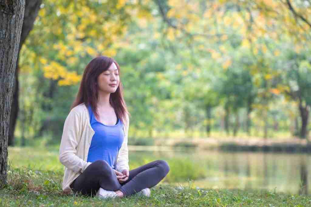 Woman-relaxingly-sitting-and-practicing-meditation-in-the-public-park