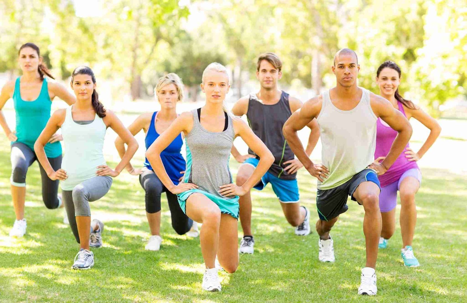 Fitness Class Performing Stretching Exercise In Park