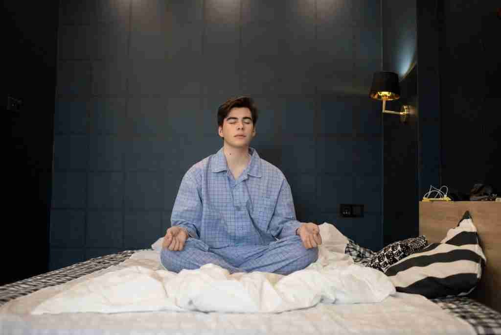 A boy meditating on his bed