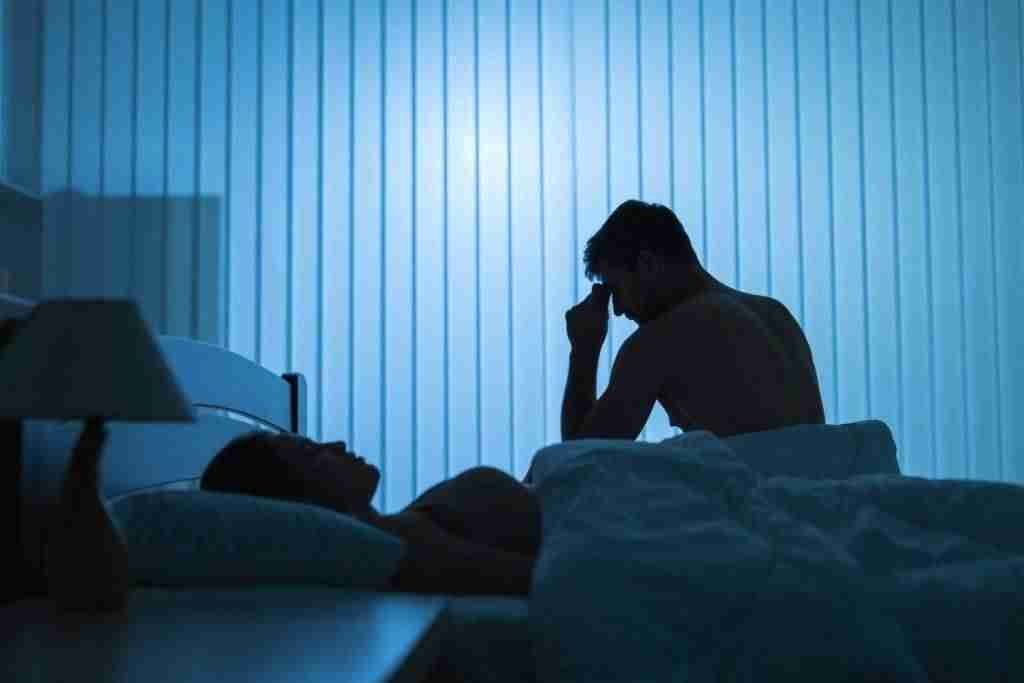 Stressed man sit near near sleeping woman in the bed.