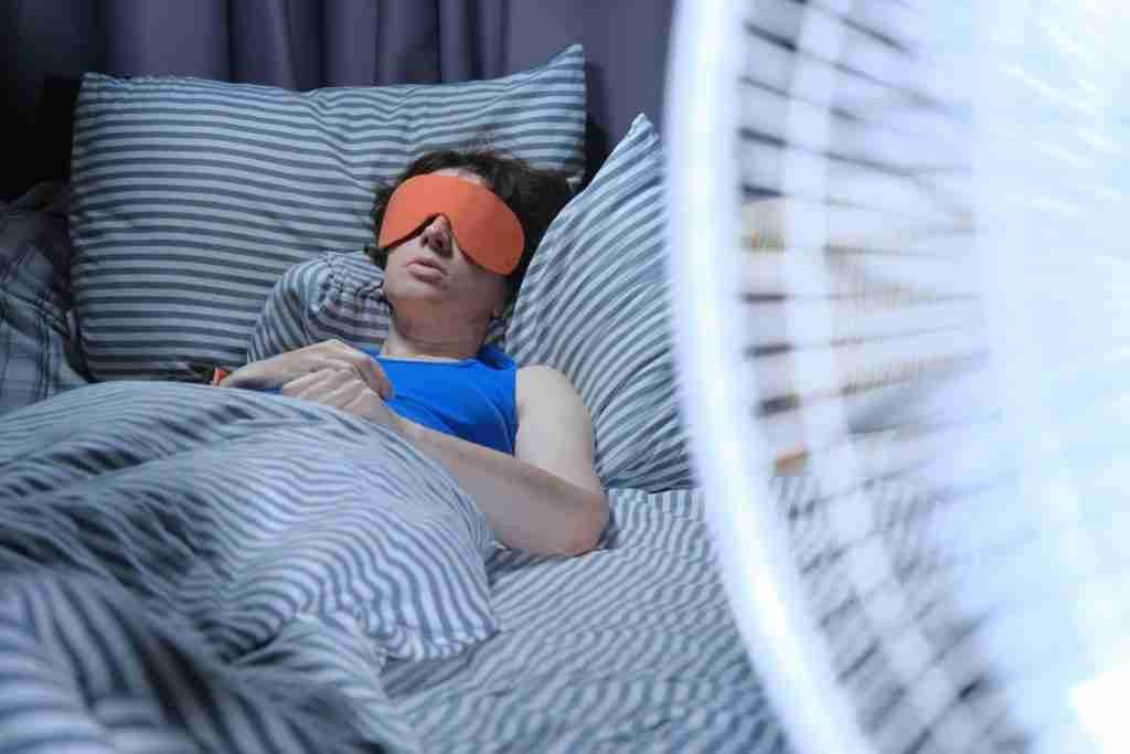 Woman is trying to sleep in the heat with a fan