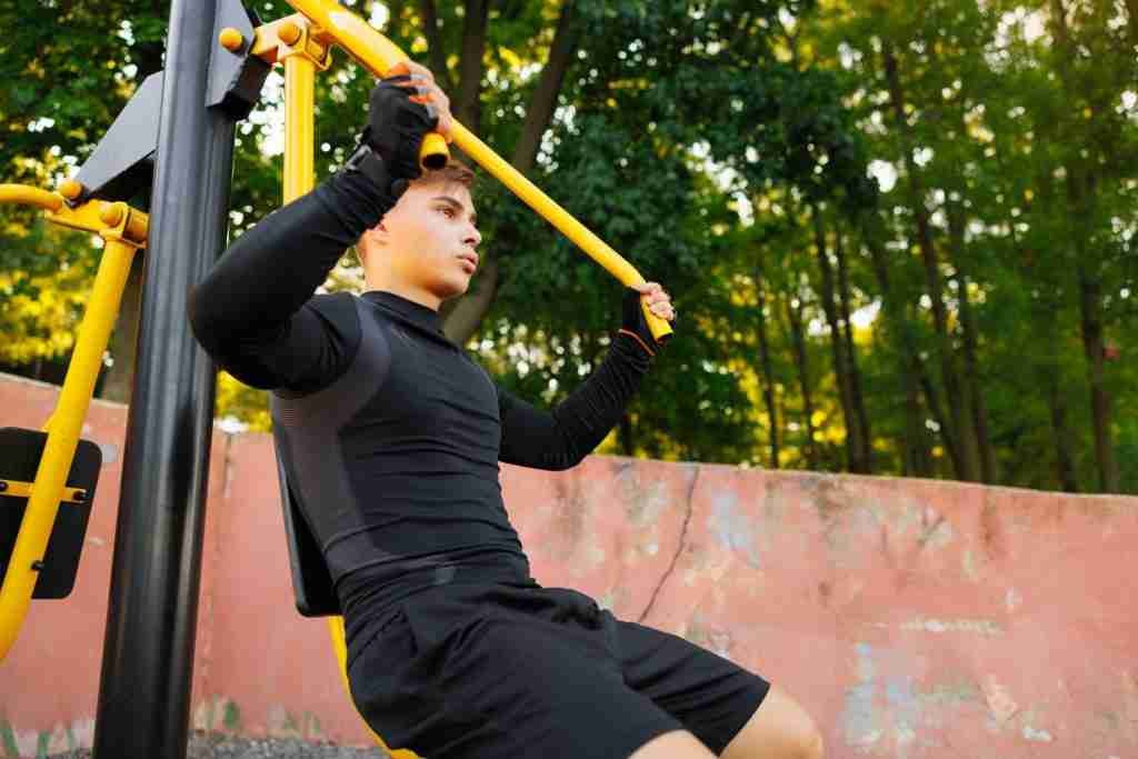 man doing pull ups on horizontal bar outdoors