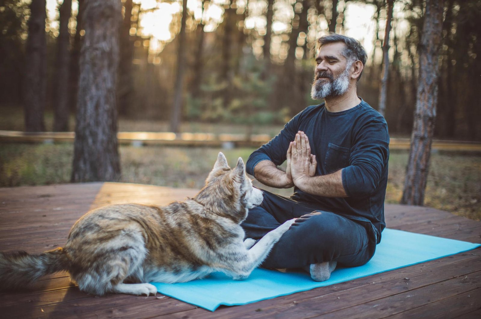 A man meditating with his dog