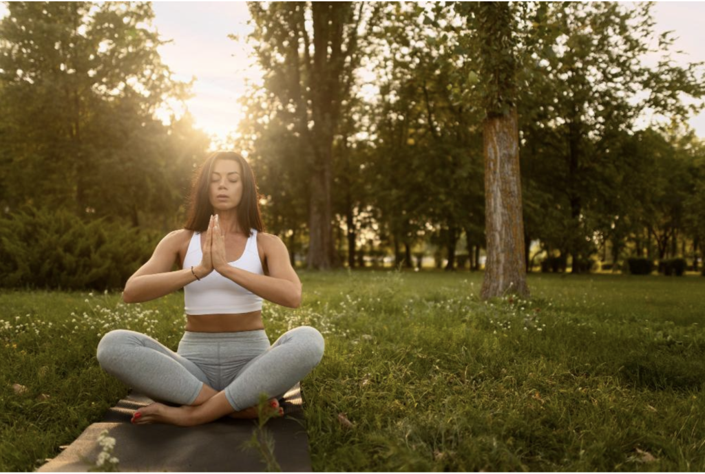 A lady meditating outdoors.